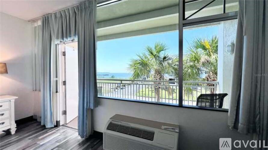 A room with a view of the beach and palm trees.