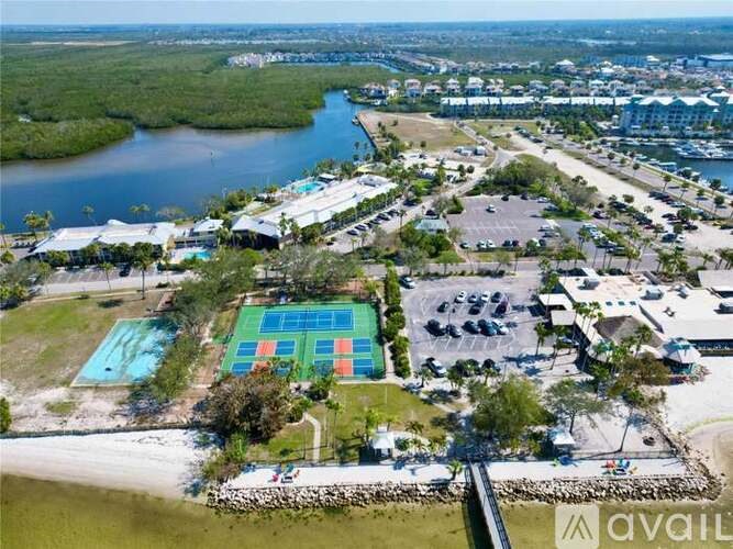 A large outdoor swimming pool with a tennis court in the middle of a parking lot.