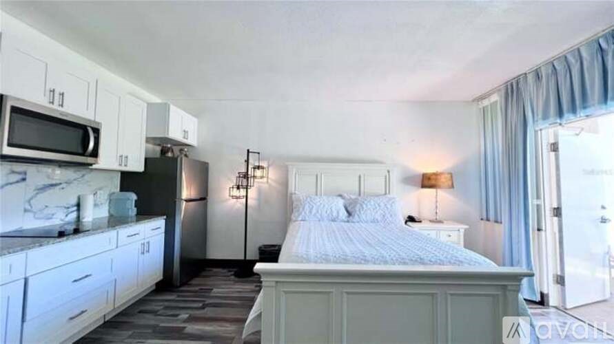 A bedroom with a bed, a microwave, and a fridge.