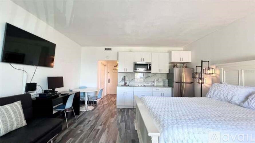 A bedroom with a bed, a couch, a desk, and a television.