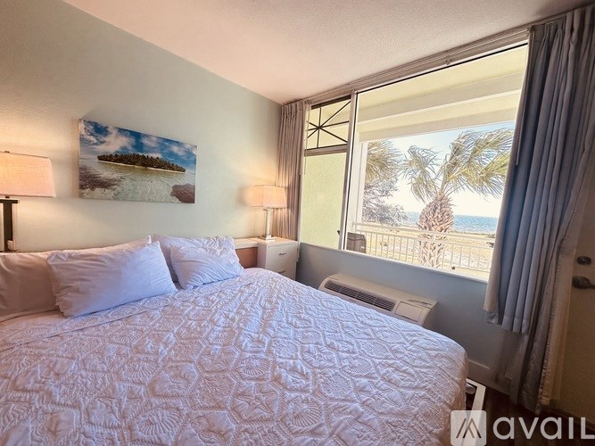 A bedroom with a large bed and a view of the beach through the window.