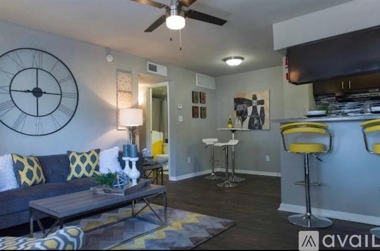 A living room with a grey couch and a large clock on the wall.