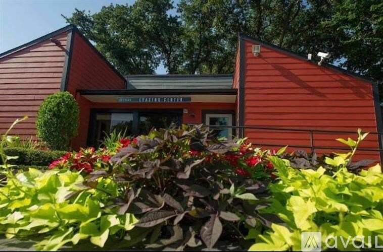 A red house with a green bush in front.