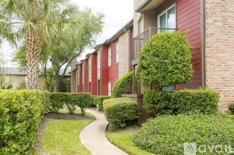 A red brick building with a green hedge in front.