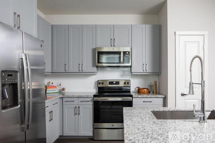 A modern kitchen with a stainless steel refrigerator and a granite countertop.