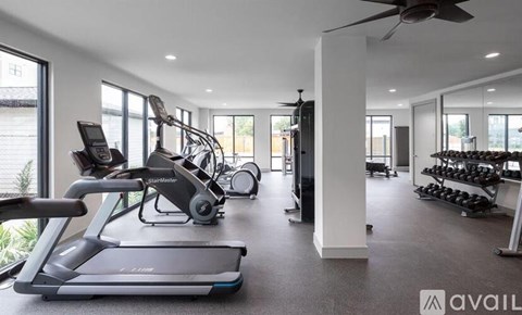 A spacious gym with treadmills, elliptical machines, and a fan.