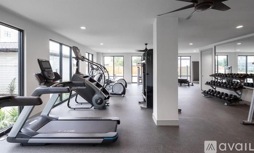 A spacious gym with treadmills, elliptical machines, and a fan.