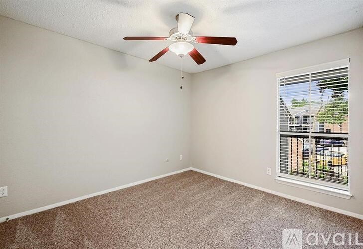 A room with a ceiling fan and a window with blinds.