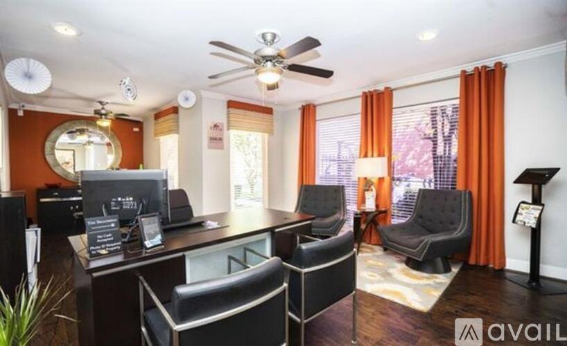 A modern office space with black furniture and a ceiling fan.