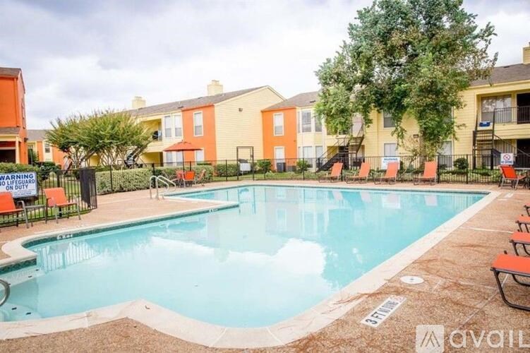 A pool surrounded by chairs and apartment buildings.