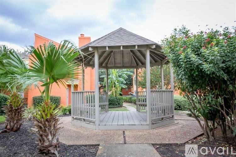 A gazebo is surrounded by plants and trees.