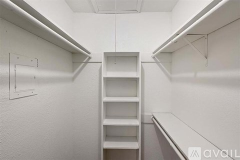 A white walk-in closet with shelves and a hanging rod.