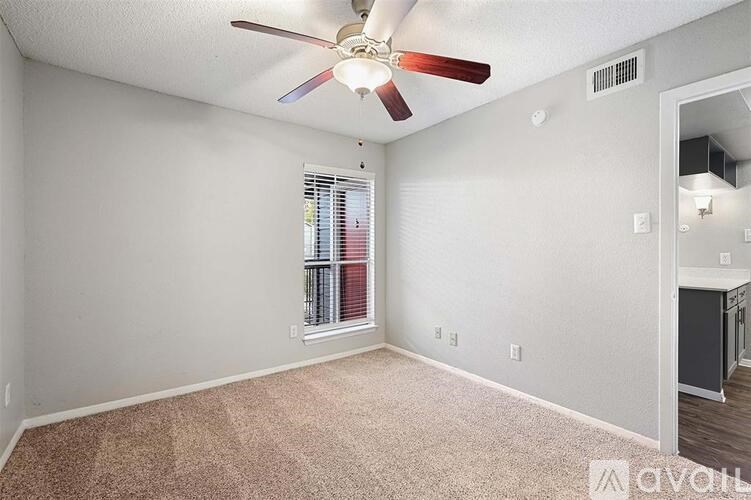 A room with a ceiling fan and a window with blinds.