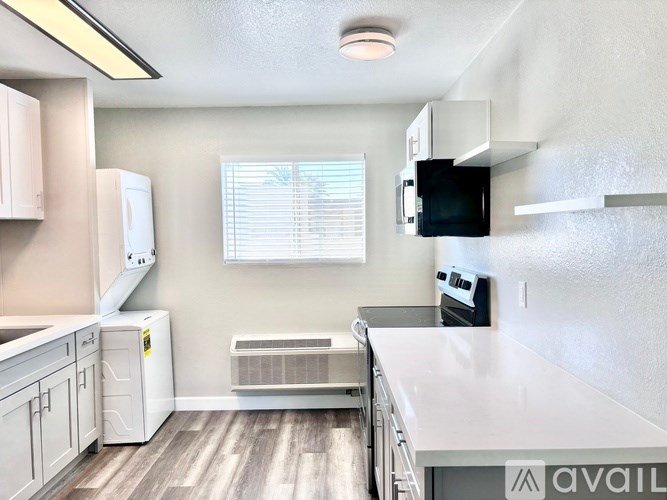 A kitchen with white cabinets and a black microwave.
