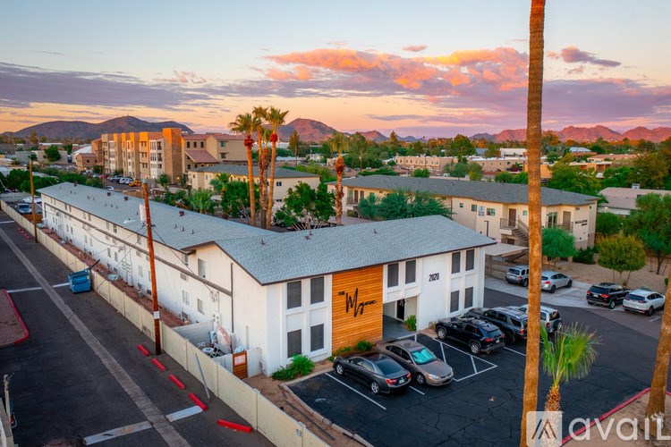 A building with a yellow logo on the side is surrounded by a parking lot.