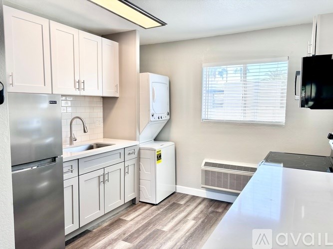 A kitchen with white cabinets and a stainless steel refrigerator.