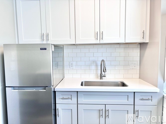 A kitchen with white cabinets and a stainless steel refrigerator.