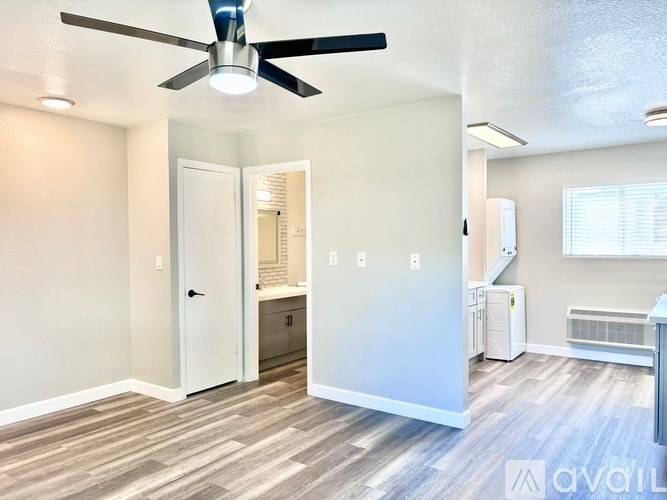 A room with a ceiling fan and light, a door, a window, and a wall-mounted heater.