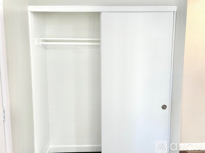A white closet with a door and a shelf.
