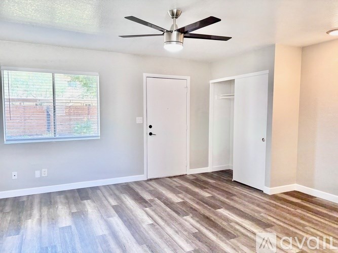 A room with a ceiling fan and a window with blinds.
