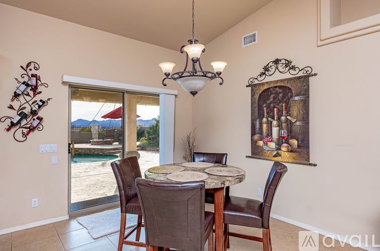 A dining room with a table and chairs and a painting on the wall.