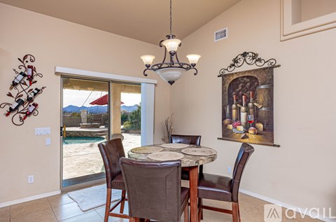 A dining room with a table and chairs and a painting on the wall.