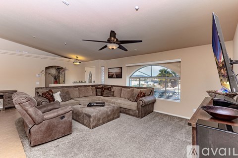A living room with a brown sofa set and a ceiling fan.