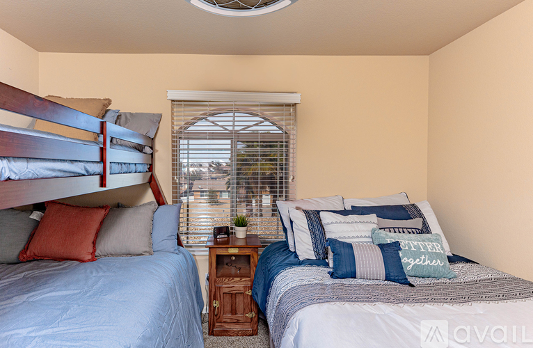 A bedroom with two beds and a window with blinds.