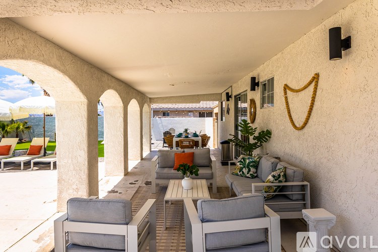A patio with white furniture and a white wall with a black speaker.