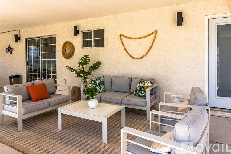 A living room with a grey couch, a white coffee table, and a smiley face on the wall.
