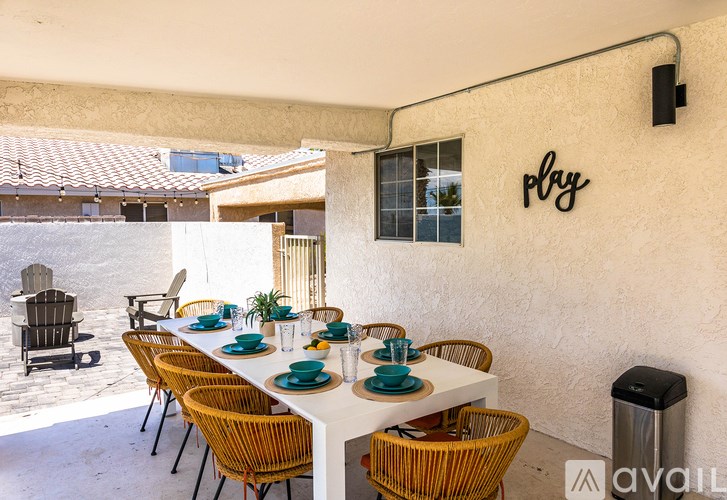 A patio with a table set for dining and chairs around it.