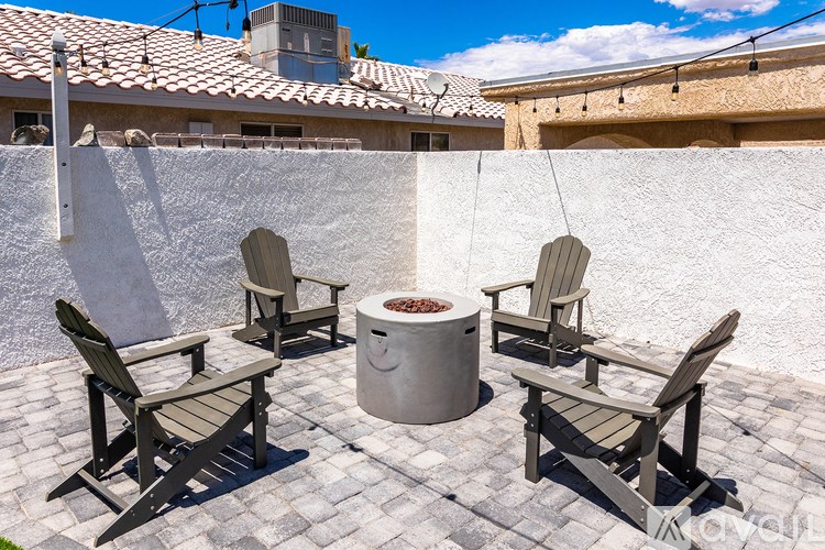 A patio with four chairs and a table with a fire pit in the middle.