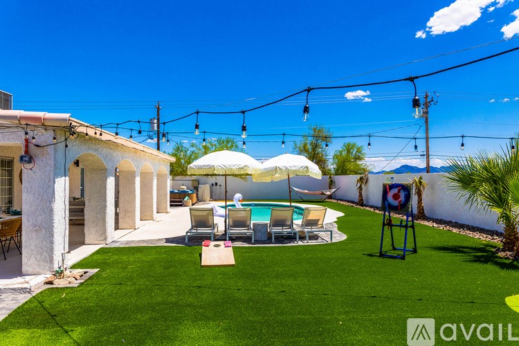 A sunny backyard with a pool and patio furniture.