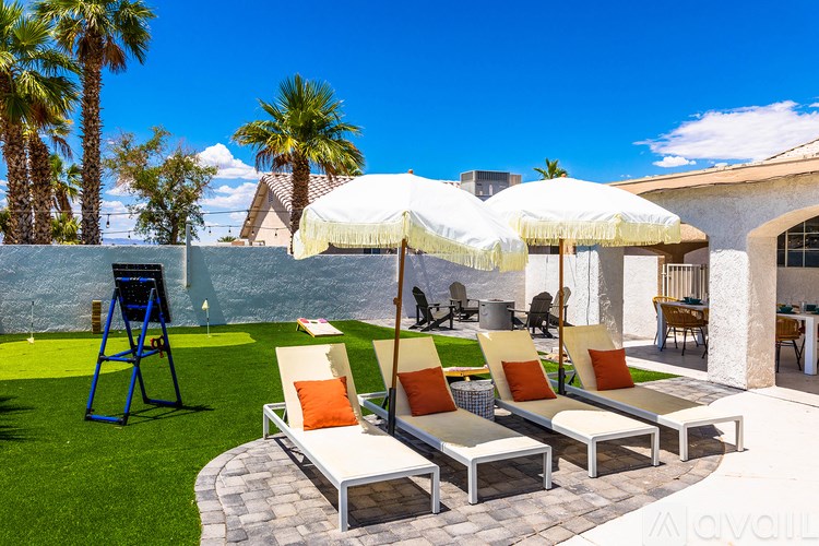 A patio with a white umbrella and four chairs.