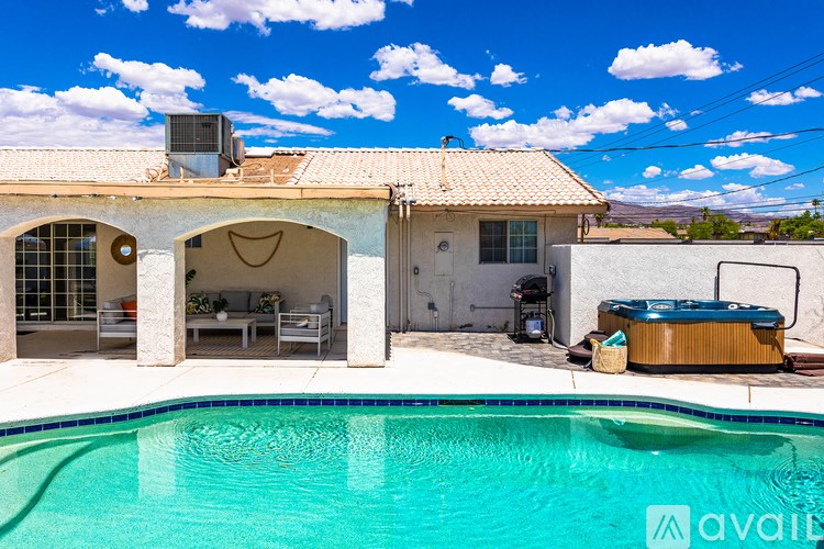 A pool in front of a house with a hot tub outside.