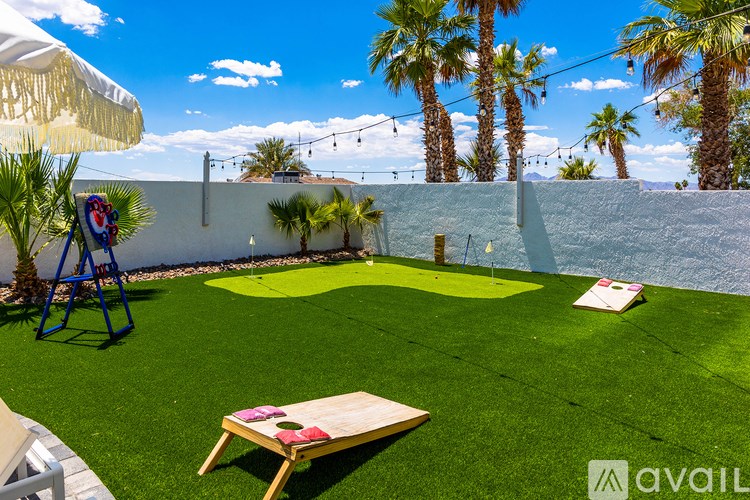 A backyard with a green lawn and palm trees.