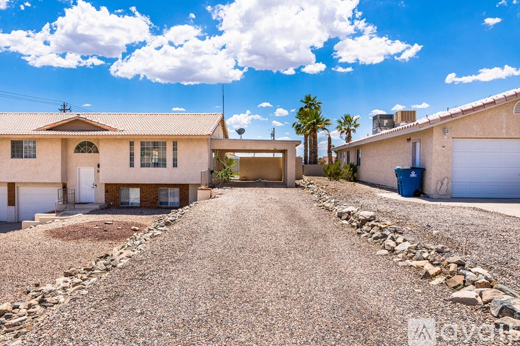A house with a gravel driveway and a stone wall in front.