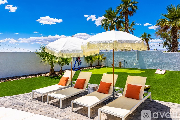 A patio with white chairs and a white umbrella.