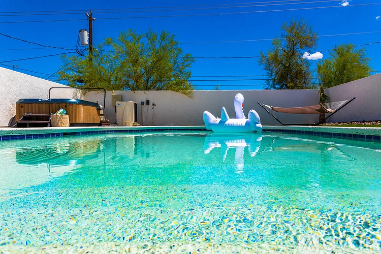 A pool with a blue tiled bottom and a white inflatable pool float.
