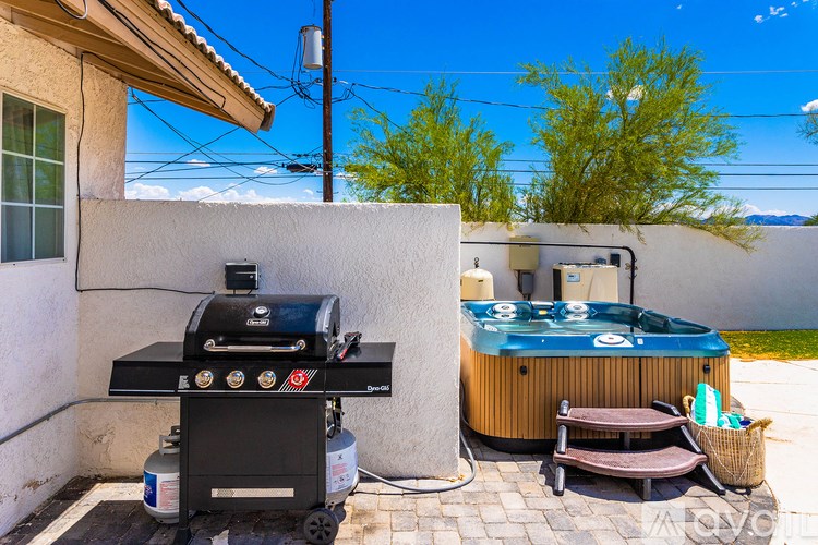A black grill is on a patio next to a hot tub.