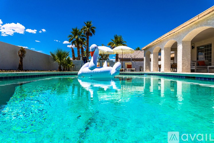 A person is floating on a swan-shaped float in a pool.