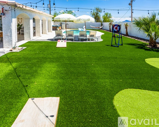 A backyard with a lawn, patio furniture, and a pool.