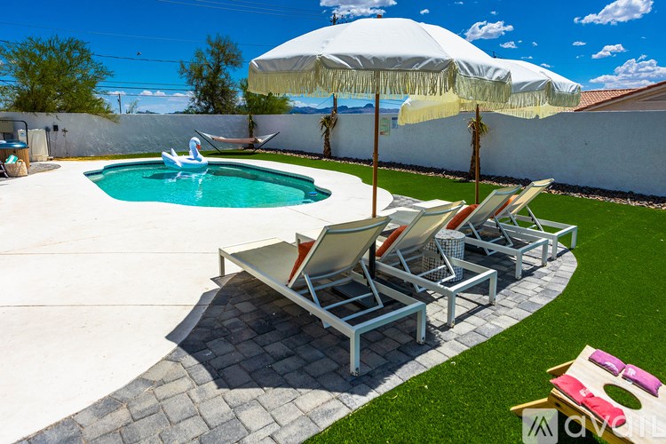 A pool with a white umbrella and chairs.
