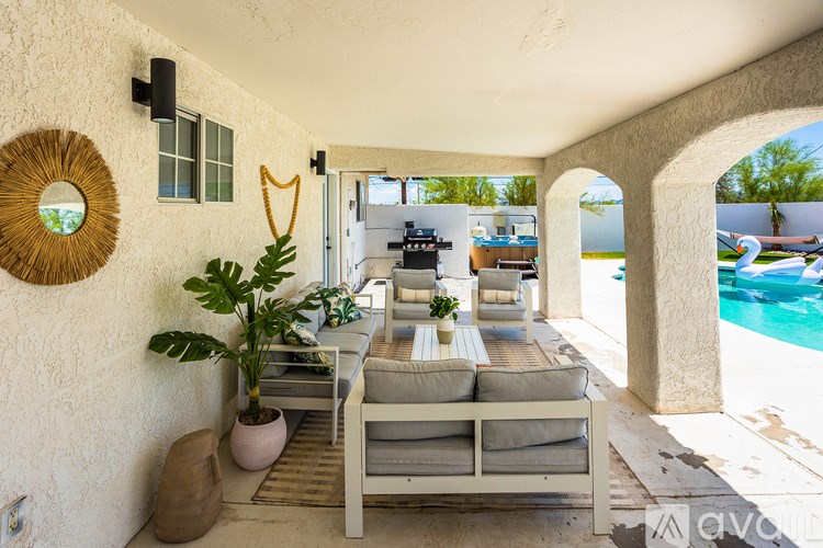 A patio with a table and chairs overlooking a pool.