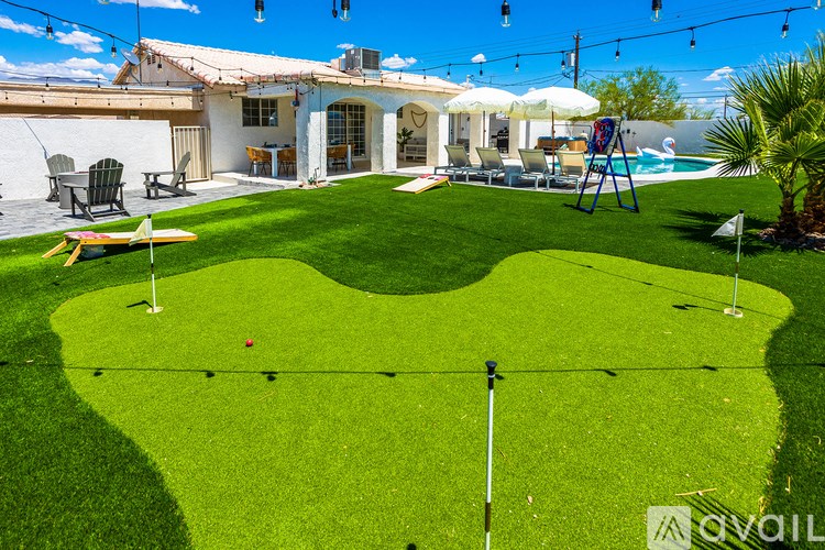A backyard with a putting green and a pool.