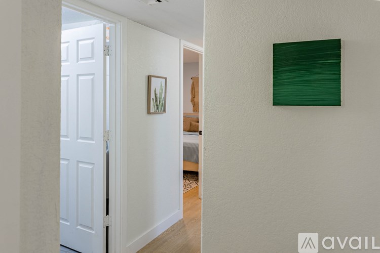 A hallway with a white door and a green picture on the wall.