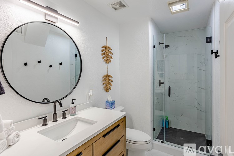 A bathroom with a white sink and a round mirror.