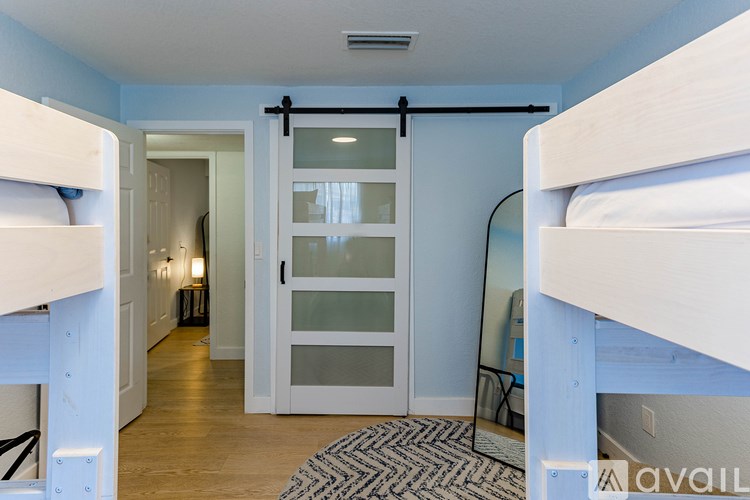 A bedroom with a white bunk bed and a mirror on the wall.