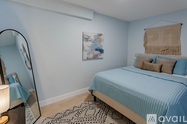 A bedroom with a bed, a mirror, and a rug.