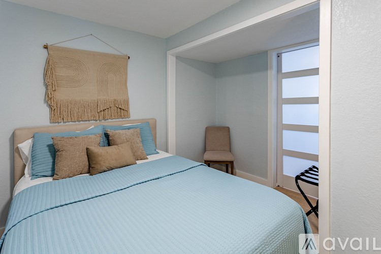 A bedroom with a bed, a chair, and a window.